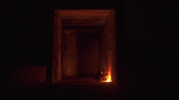 Two mans in a dark sits near the fire in giant abandoned building — Stock video