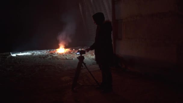 Camera man shoots a big fire in dark abandoned military hangar. — Vídeo de stock