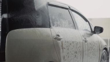 Oto yıkama işçisi, evrensel arabayı temizlemek için yüksek basınçlı su jeti kullanır.