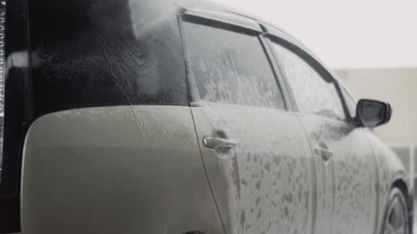 Oto yıkama işçisi, evrensel arabayı temizlemek için yüksek basınçlı su jeti kullanır. — Stok video