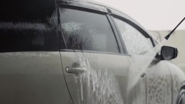 Araba yıkama servisindeki bir arabadan yüksek basınçlı temiz köpük jeti.
