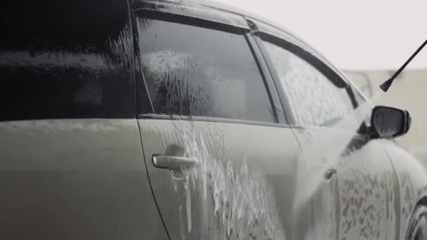 Waterstraal onder hoge druk schoon schuim van een auto op carwash service — Stockvideo