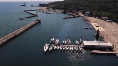 Huzurlu bir körfezde büyük bir su kırıcı ve bir sürü beyaz yatla hava manzarası. 
