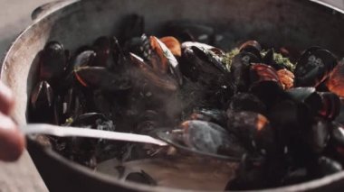 Şef krema sosuna midye katmak için kepçe kullanıyor. 