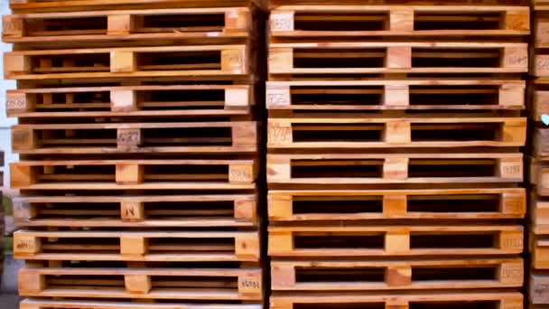 Un movimiento cerca de un montón de paletas de madera pilas conservadas en el almacén de entrega — Vídeos de Stock