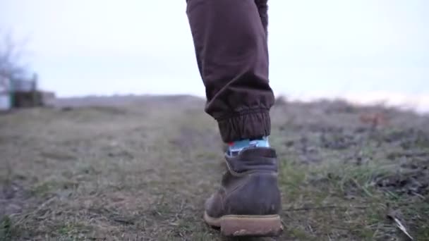 Πόδια σε βαριές μπότες ενός αγνώριστου άντρα που περπατάει σε βρώμικους λόφους — Αρχείο Βίντεο