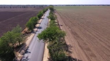 Dinamik hava görüntüleri kırsal alanda beyaz bir arabanın etrafında hareket ediyor.