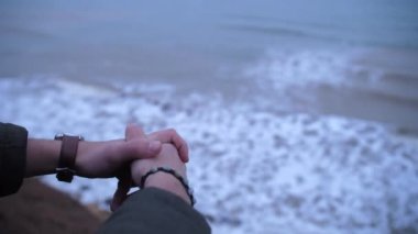 Yalnız genç adamın elleri kirli deniz suyunun üzerinde uçurumun kenarında oturuyor.