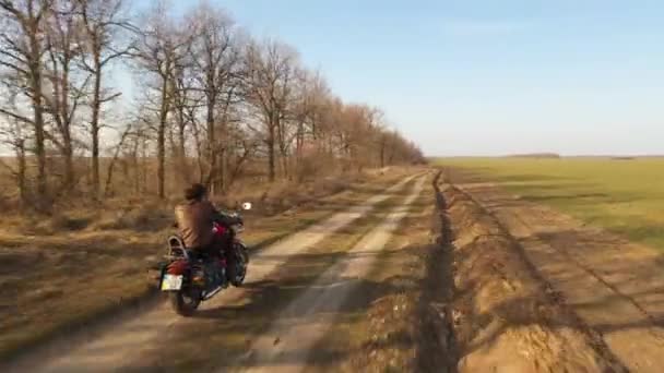 Siguiendo una moto roja paseando por caminos de tierra en el campo — Vídeos de Stock