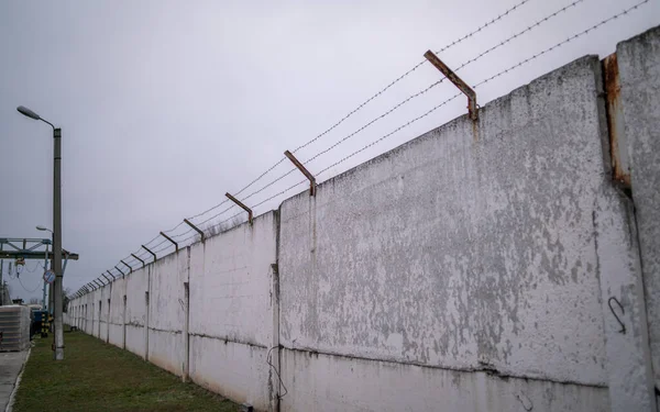 Eski beton bir çitin tepesindeki paslı dikenli tel. 