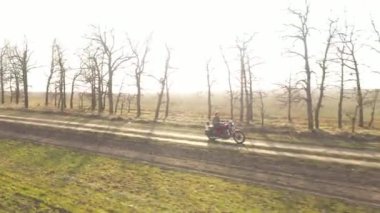 Güneşli sonbahar kır yolunun üzerinde uç. Kırmızı eski stil bisikletli motorcu