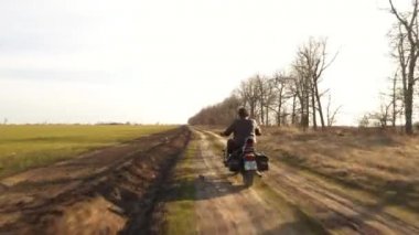 Deri ceketli bir adam sonbahar güneşli bir günde helikopterle off-road 'a biniyor.