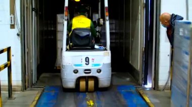 Forklift moves from a warehouse inside trucks cargo trailer