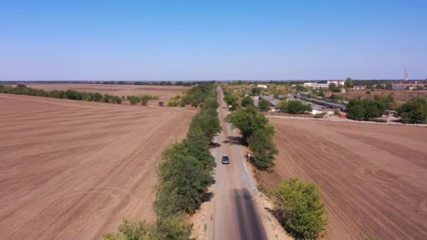 Aerial tracking the car that moves form dirt road to a new asphalt way — Αρχείο Βίντεο