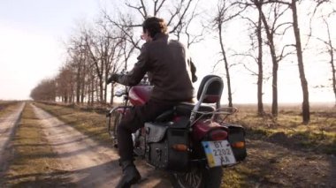 Yavaş çekimde genç motorcu, kırmızı helikopterde, anlamlı bir şekilde geriye bakıyor.