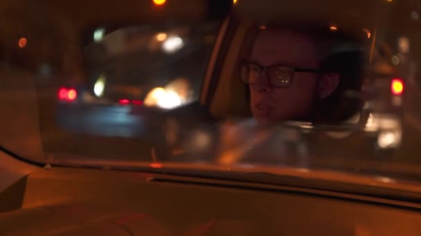 Young guy filmed in a rearview mirror while he expressive talks in time of drive — Stock Video