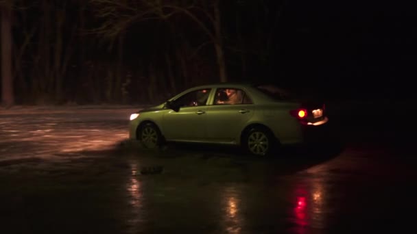 도시에서 멀리 떨어진 곳에서 밤이면 호수 표면의 얇은 얼음 위에 자동차가 떠다니다 — 비디오