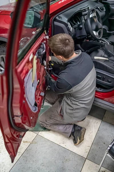 Cara mecânica no serviço de automóvel ficar de joelhos perto da porta do carro — Fotografia de Stock