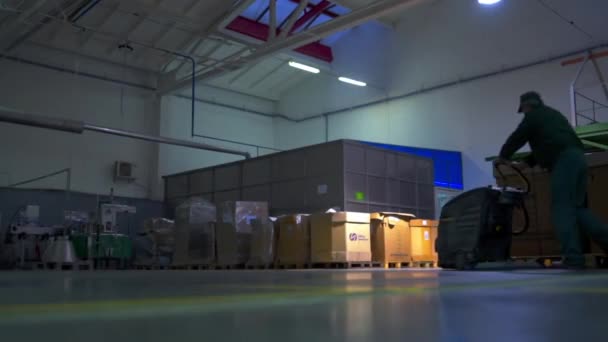 Worker with a washing machine walks in a big storage house — Stockvideo