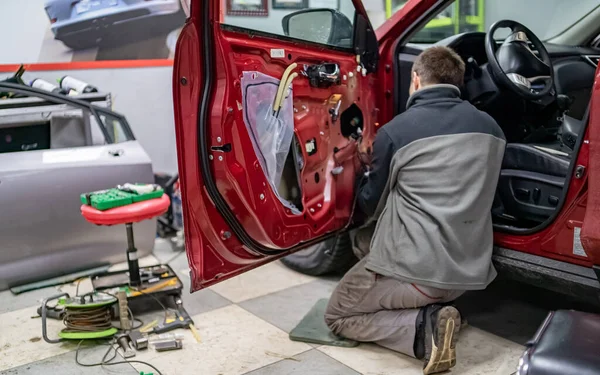 Cara mecânica no serviço de automóvel ficar de joelhos perto da porta do carro — Fotografia de Stock