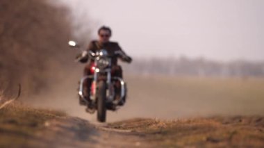 Kırmızı gözlüklü genç, kıvırcık motorcu kırmızı helikoptere biniyor.
