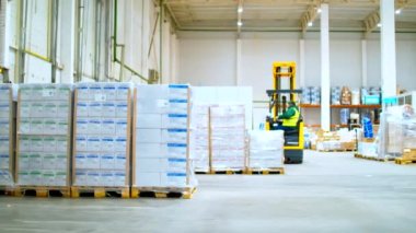 Turuncu forklift büyük bir depoda geziniyor.