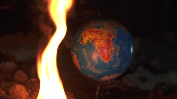 Gros plan du feu brûlant près du globe sur le sol détruit avec beaucoup de roches — Video