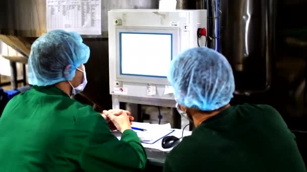 Dois trabalhadores de fábrica em ternos de proteção sentam-se perto de uma tela do painel de controle — Vídeo de Stock