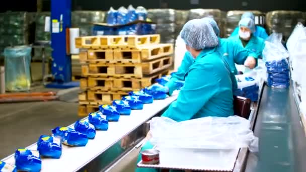 Les employeurs de femmes sur l'usine de pâtes prennent des paquets de pâtes bleues de la ligne de convoyeur — Video