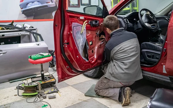 Cara mecânica no serviço de automóvel ficar de joelhos perto da porta do carro — Fotografia de Stock