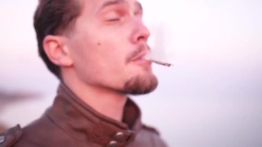 Sinirli bir gencin yakın çekimi açık havada marihuana içiyor.