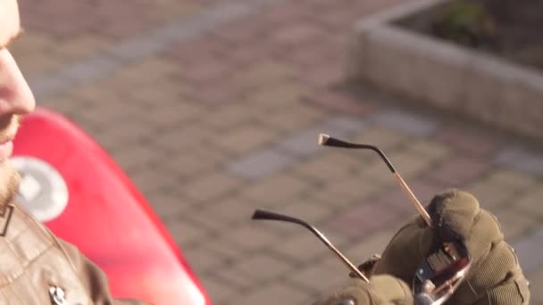 Zapętlone wideo kręconego młodzieńca w garniturze motocyklowym włożył czerwone okulary i odłożył — Wideo stockowe