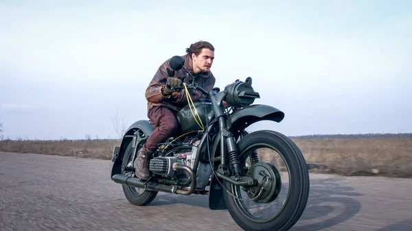 Вид сбоку на стильного крутого мужчину в кожаной куртке за рулем винтажного мотоцикла — стоковое фото