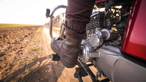 Мотоцикл быстро едет по грунтовой сельской дороге через поле осенью солнечного дня — стоковое фото