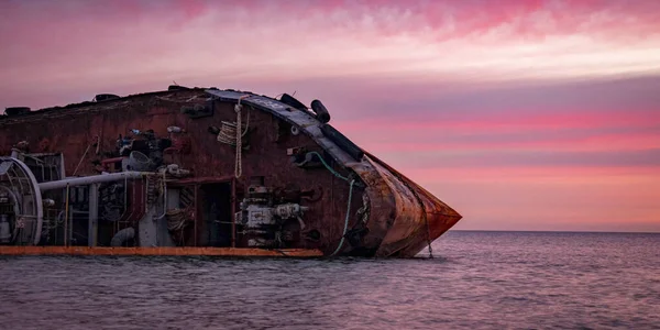 Sunrise time photo of rusty wreaked ship on the purple sea surface — Stock Photo, Image