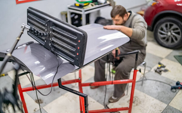 Работник автосервиса с бородой, ручное фото в процессе работы