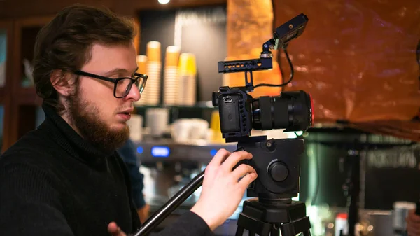 Professional operator uses a camera on tripod to set a frame in the cafe