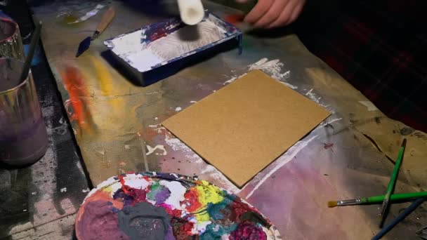 年轻的画家正在用一层底漆在架子上准备床单. — 图库视频影像