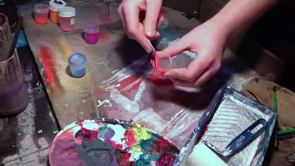 Handen van een mannelijke kunstenaar bereidt verven voor het tekenen van een beeld van vloeibare kunst. — Stockvideo