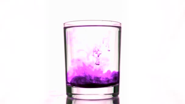 Fall av en lila bläck ström i glas med rent vatten — Stockvideo