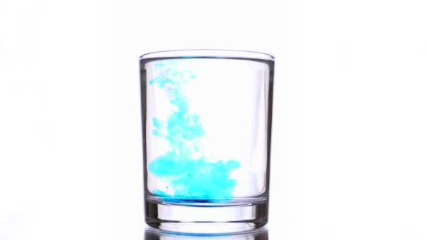 Boom kleine druppels licht blauwe inkten druipt in zuiver water glas — Stockvideo