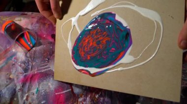 Statik kamera, profesyonel erkek ressamın akrilik boyalarla tuvali eğdiğini gösteriyor.