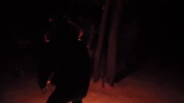 Kışın gece ormanında kaybolmuş bir adam elinde meşaleyle etrafta koşuşturuyor.