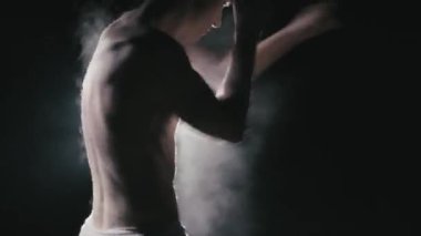 Sıkı çalışan bir boksörün etrafında çok duman var. Karanlık bir sahnede güzel bir boksör.