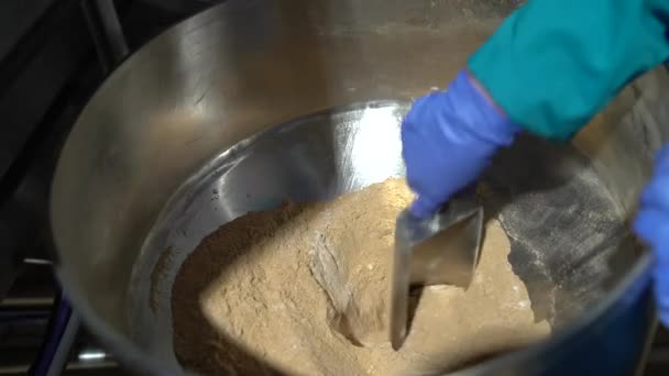 Hands of a woman worker mixing spices in the big metal funnel to develop sauce — Stock Video