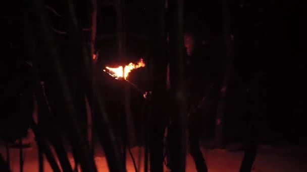 Gevreesde kerel met een fakkel loopt in de nacht winterbos en toont vuur rond — Stockvideo