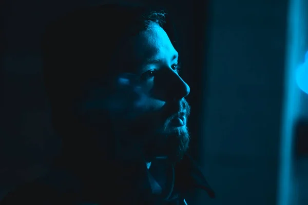 담배를 피우고 있는 잘생긴 남자의 모습은 어두운 파란색 조명을 받은 후드를 쓴 남자의 모습 로열티 프리 스톡 사진