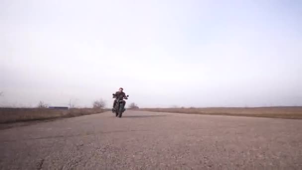Jong kibbelen op vintage motorfiets snelle rit dichter van een ver — Stockvideo
