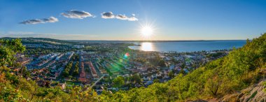 Huskvarna Skyline 'ın yukarısından günbatımı manzarası Jonkoping, Smaland, İsveç yakınlarındaki Vattern Gölü' ne yansıyor..