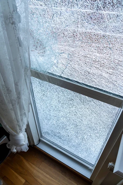 Broken balcony glass door window with shattered glass, burglar entering through the balcony window. Selective focus.